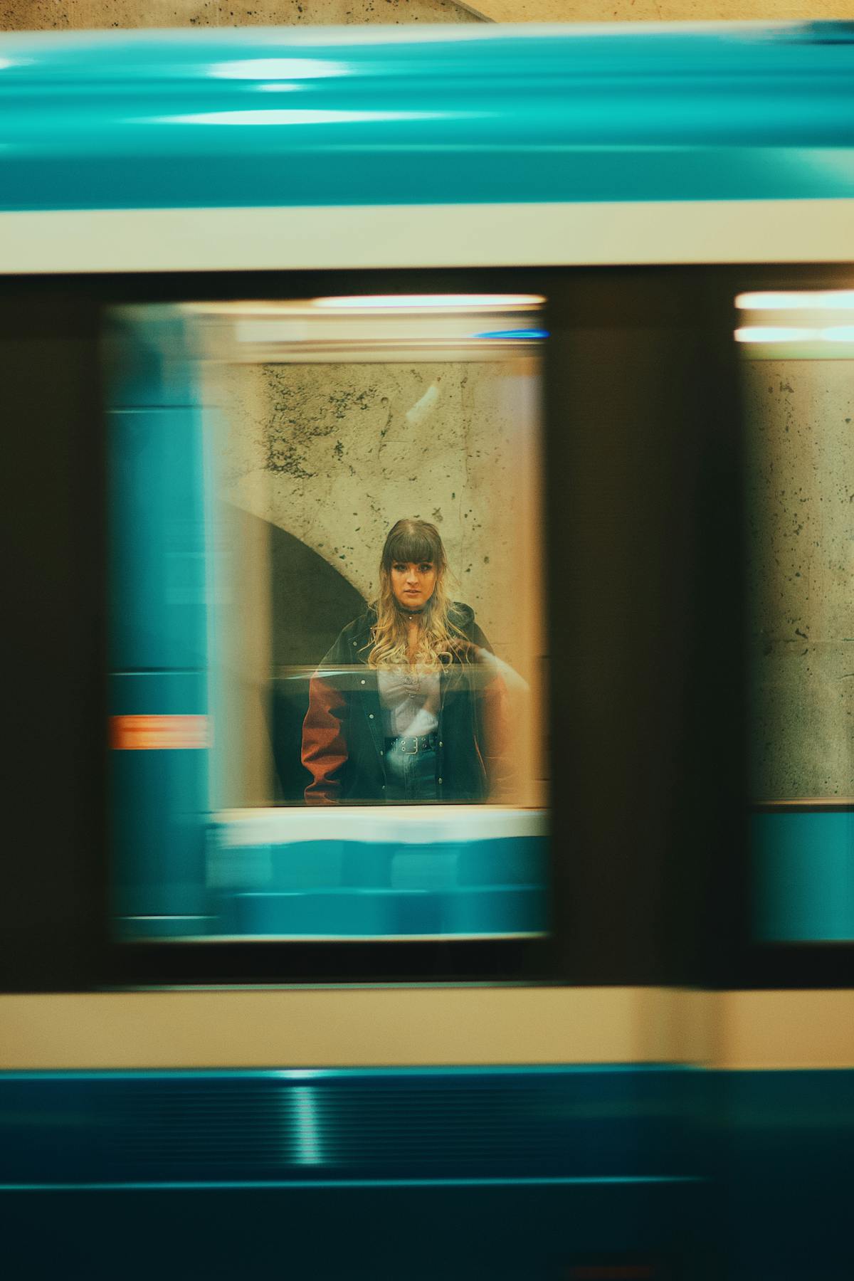 Woman seen through a moving metro train window — referencing Hannah Starkey's exploration of women in transit and public space