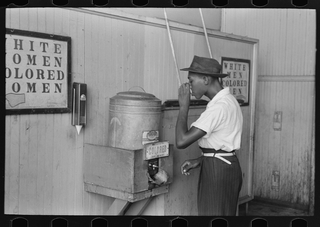 Man drinking at segregated 'Colored' water cooler in streetcar terminal, Oklahoma City