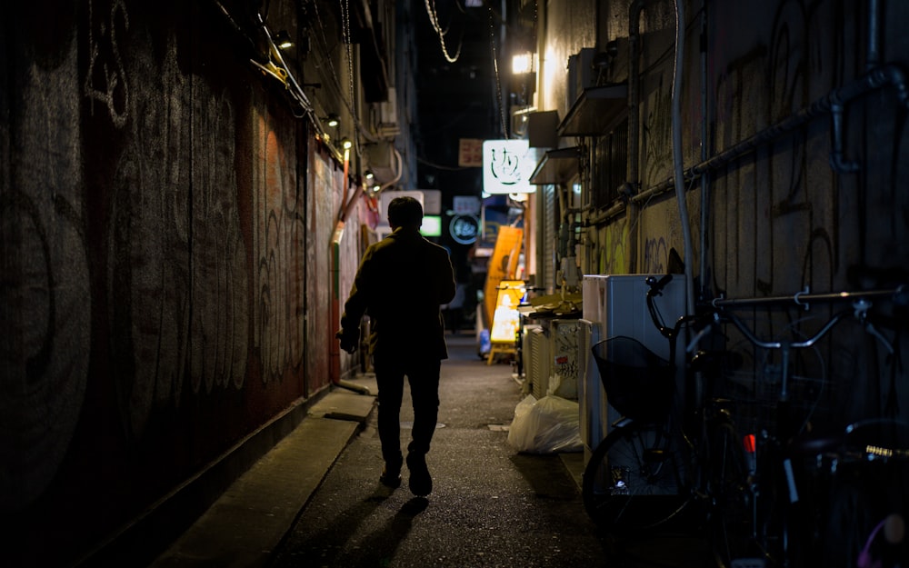 Silhouetted figure walking through a narrow alley at night, evoking diCorcia's Streetwork series