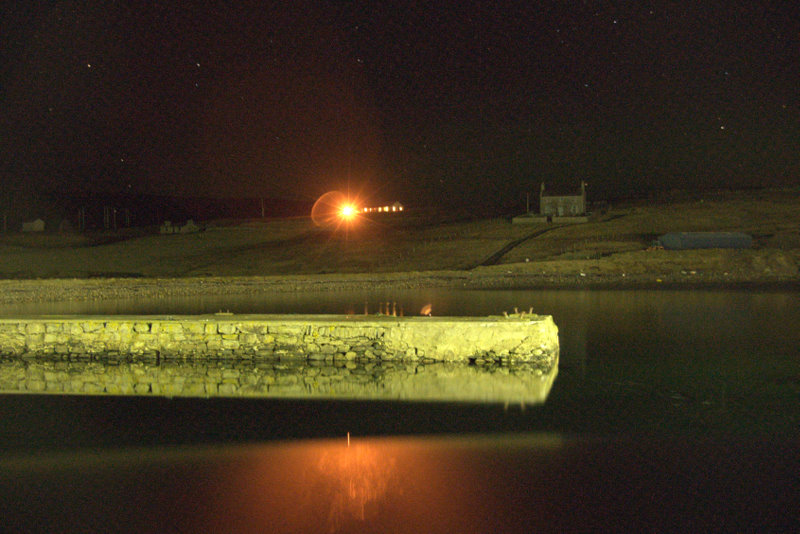 House on a dark hillside with illuminated window at night in Gutcher, Shetland — evocative of Todd Hido's nocturnal suburban photographs